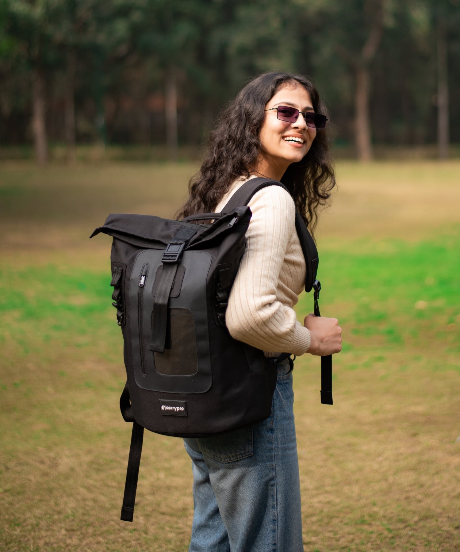 Woman wearing CarryPro roll-top backpack outdoors in a park
#color_black