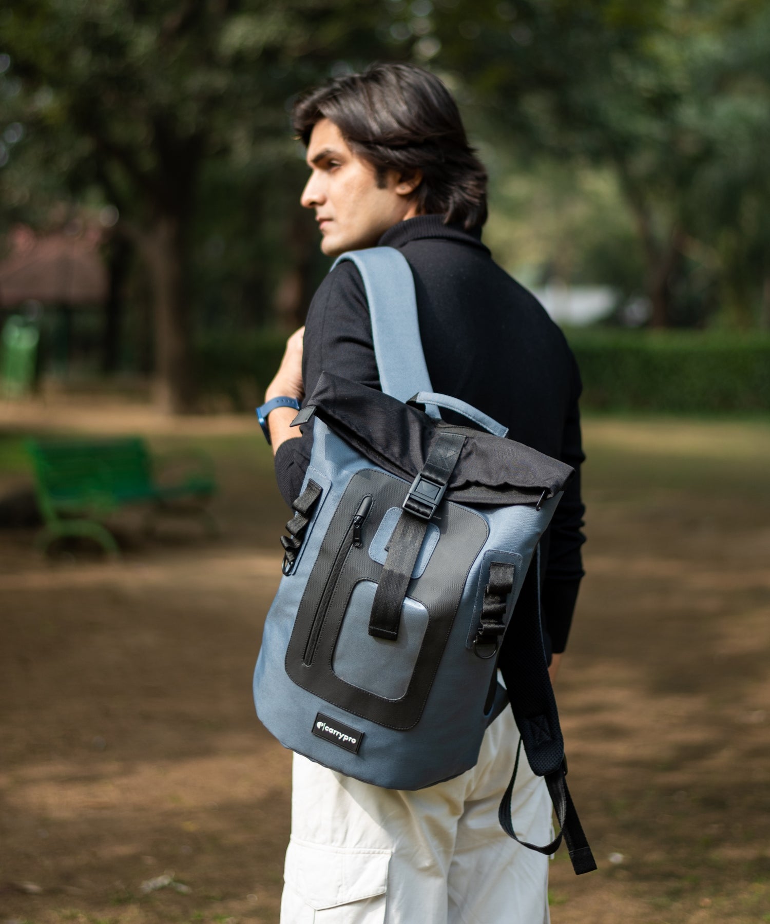 Model carrying CarryPro roll-top backpack on an urban street
#color_space grey